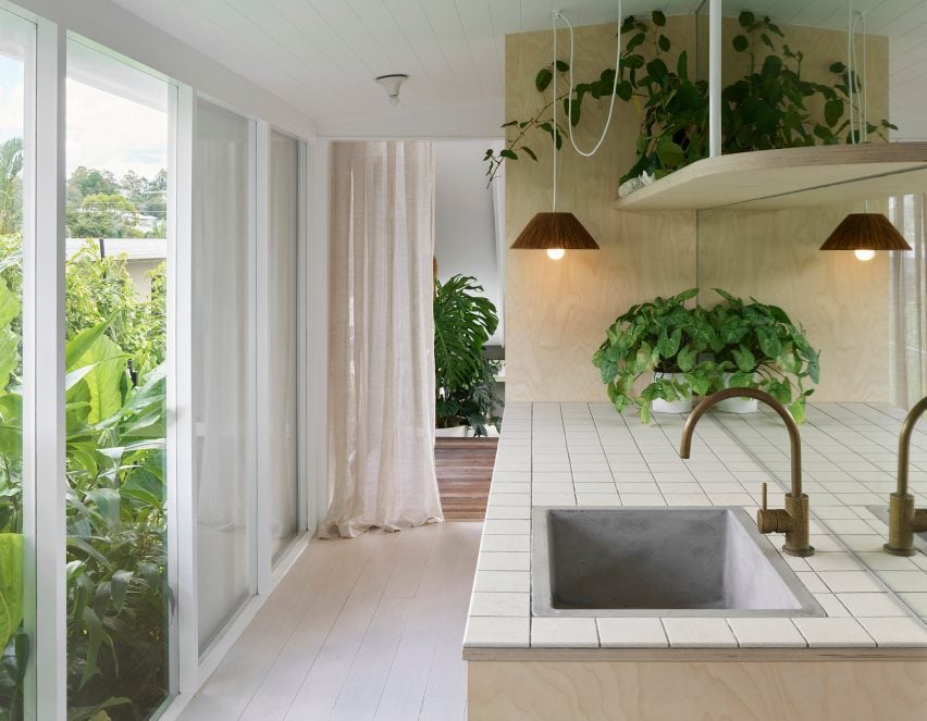 Белая кухня в Cascade House от John Ellway с застекленными дверями, ведущими в сад