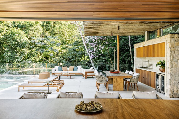VJC Iporanga House / David Bastos + Marina Salles Arquitetura e Interiores - Фотография интерьера, гостиная, стол, стул, балка, патио